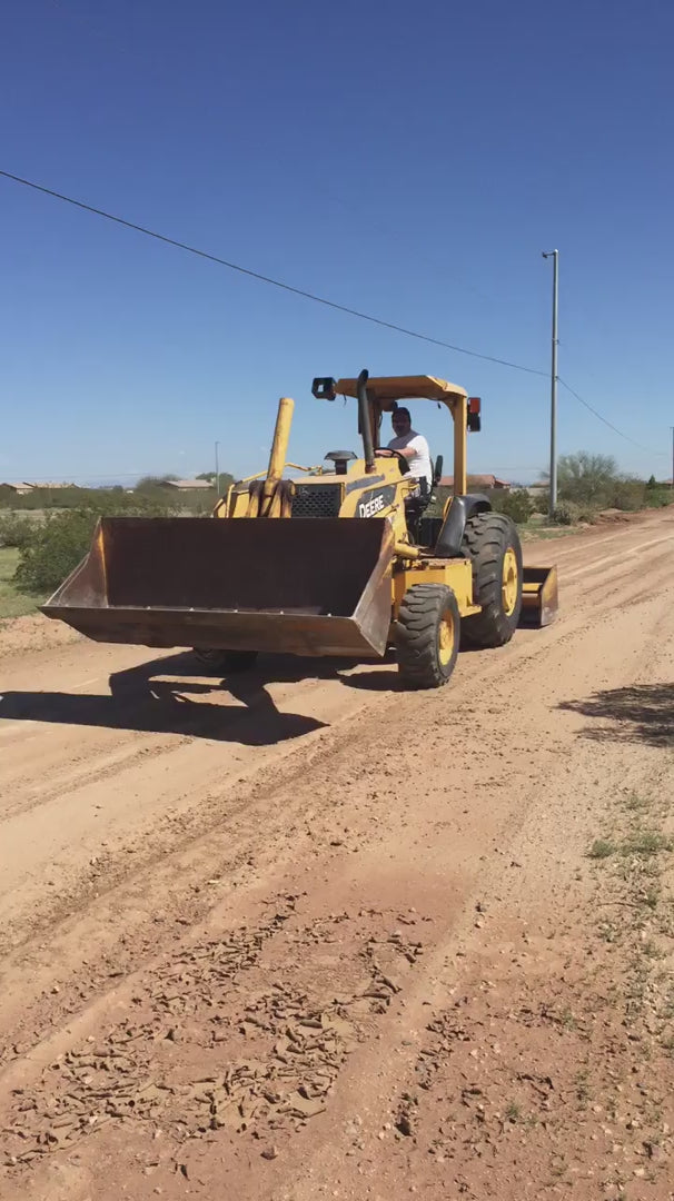 A man driving a yellow tractor across the Arizona desert, captured as a tribute to the founder of Shef’s Farms.